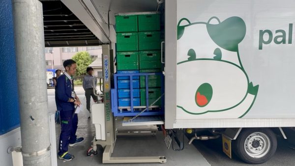 パワーリフターでドーリーごと荷を上げてトラックに積み込む様子