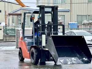 宮城県内のヤードで稼働するPCSのフォークリフト。アタッチメント「雪かきバケット」にて雪かき作業をする様子。